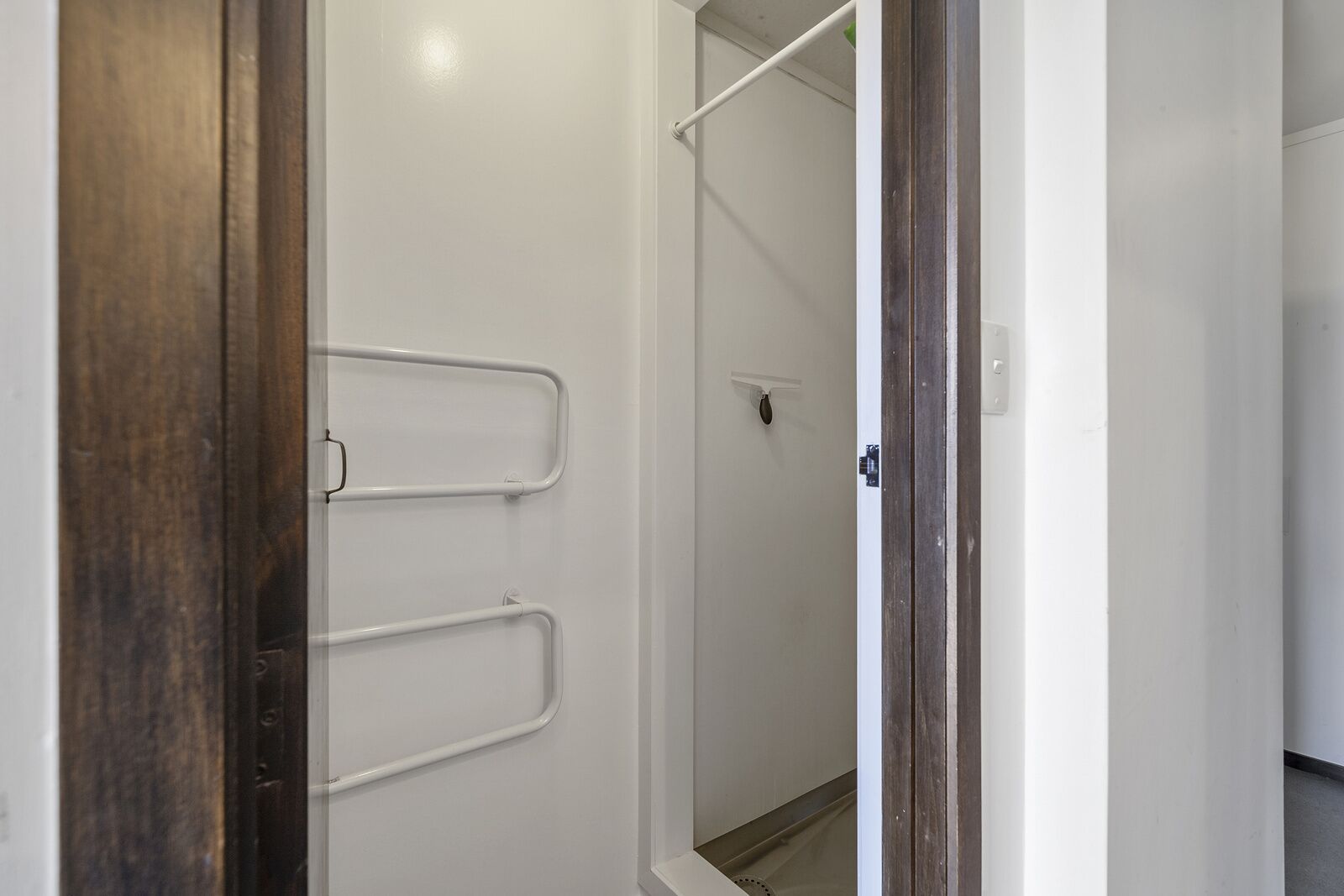 Una puerta que da a un baño con ducha y un perchero para toallas.