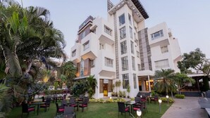 Un hotel de varios pisos con terraza al aire libre y palmeras.