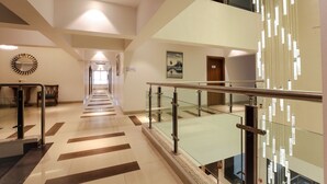 Un moderno vestíbulo de hotel con barandilla de cristal, una escalera y vistas al piso superior.