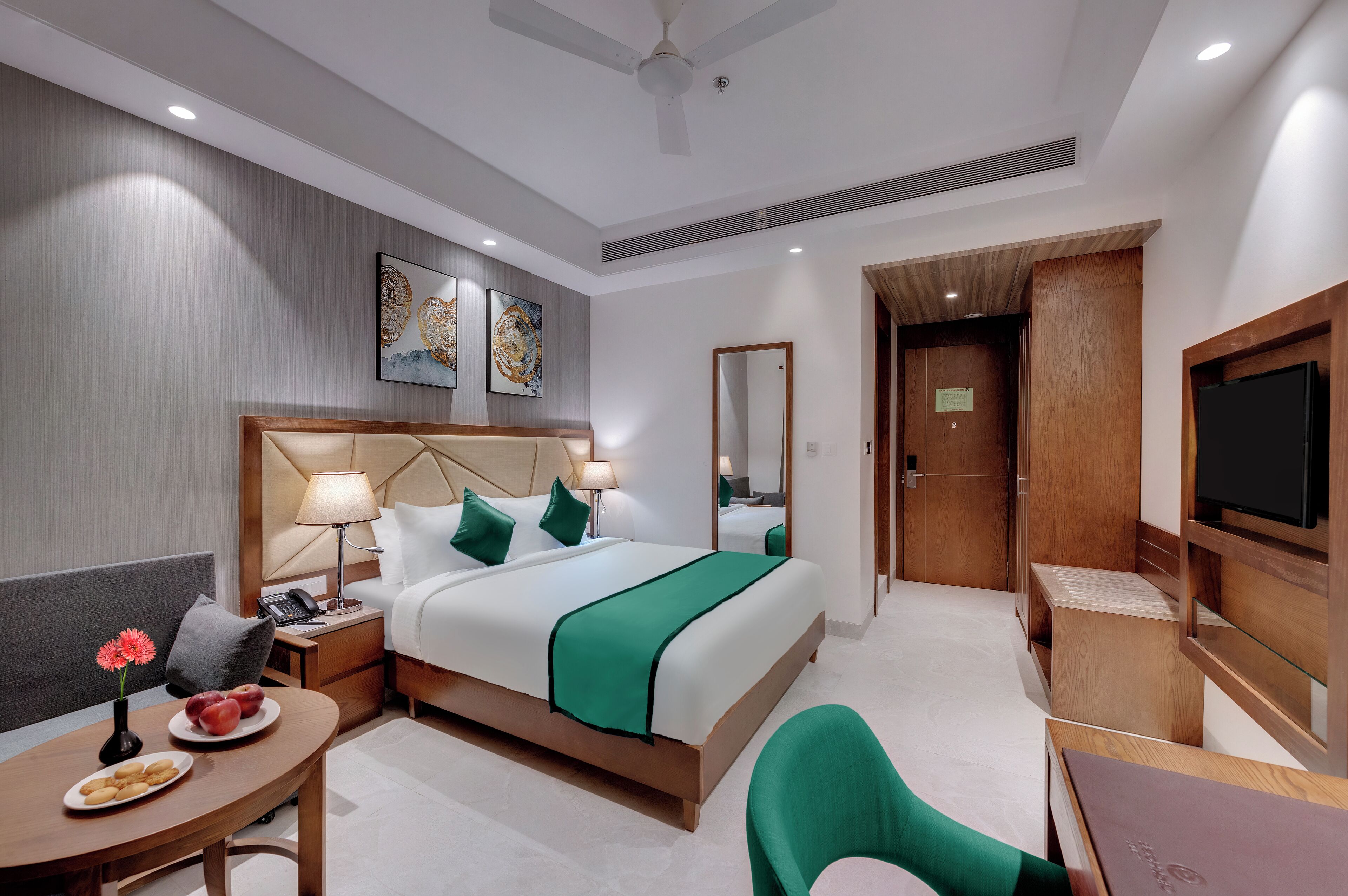 A hotel room with a bed, bedside table, lamp, and a TV.