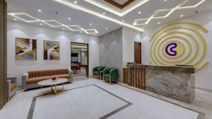 A modern lobby with a reception desk, seating area, and artwork on the walls. - Click Hotel Aurangabad (Chhatrapati Sambhajinagar)