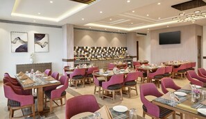 Un restaurante con varias mesas y sillas, una zona de bar y obras de arte en las paredes.