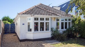 Une maison de plain-pied avec un toit en tuiles, des murs extérieurs blancs et de nombreuses fenêtres.