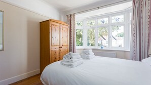 Une chambre avec un grand lit, une armoire en bois et une fenêtre avec des rideaux.