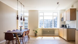 Een moderne keuken met houten kasten, een eettafel met stoelen en een groot raam met uitzicht op de stad.