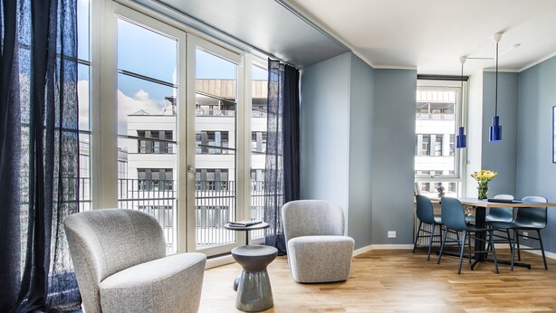 Een moderne woonkamer met grote ramen, een eethoek en uitzicht op de stad.