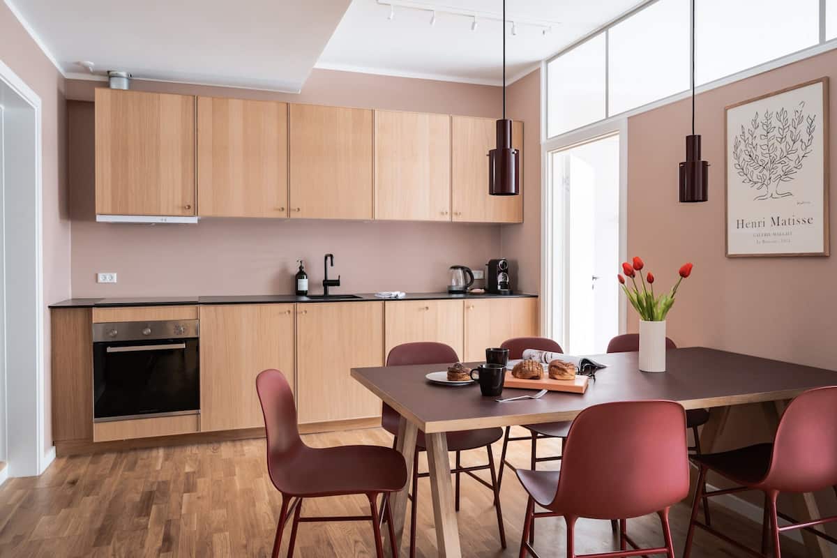 Une cuisine moderne avec des meubles de rangement en bois, une table à manger avec des chaises et une machine à café.