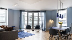 Een moderne woonkamer met een bank, een salontafel en een eethoek met stoelen en een tafel.