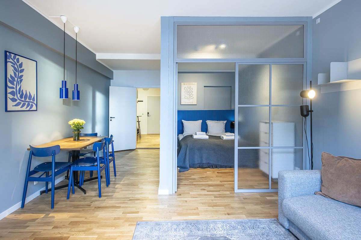 Une chambre moderne avec une grande porte coulissante, un lit avec une literie bleue et une table de chevet.