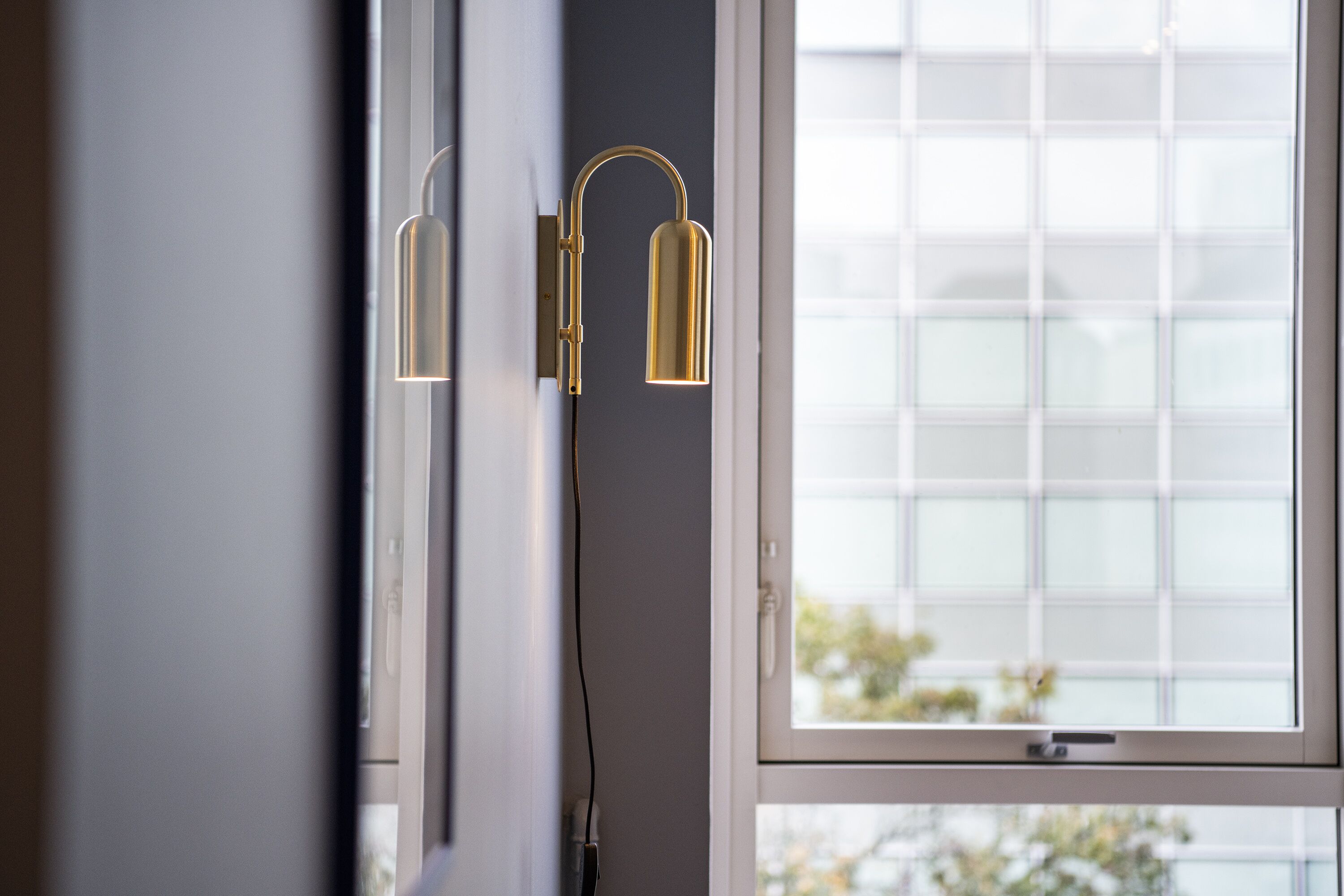 A modern interior with a window and a wall-mounted light fixture.