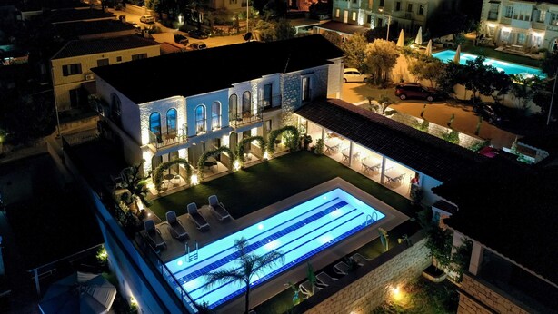 An aerial view of a hotel with a swimming pool, outdoor seating, and a well-lit courtyard. - Cemal Alaçatı Hotel (Cesme)