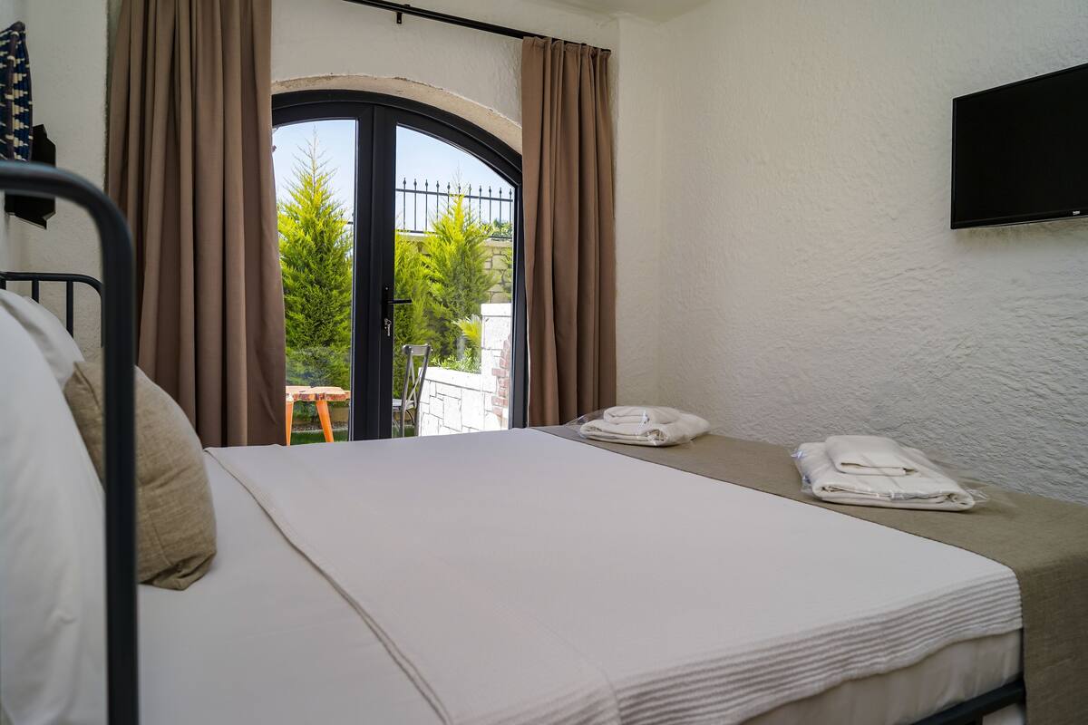 Ein Hotelzimmer mit Bett, Wandfernseher und einem Vorhangfenster.