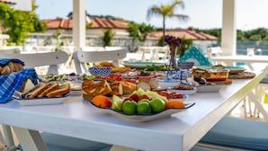 A table set with various food items and a view of a pool and palm trees. - Cemal Alaçatı Hotel (Cesme)
