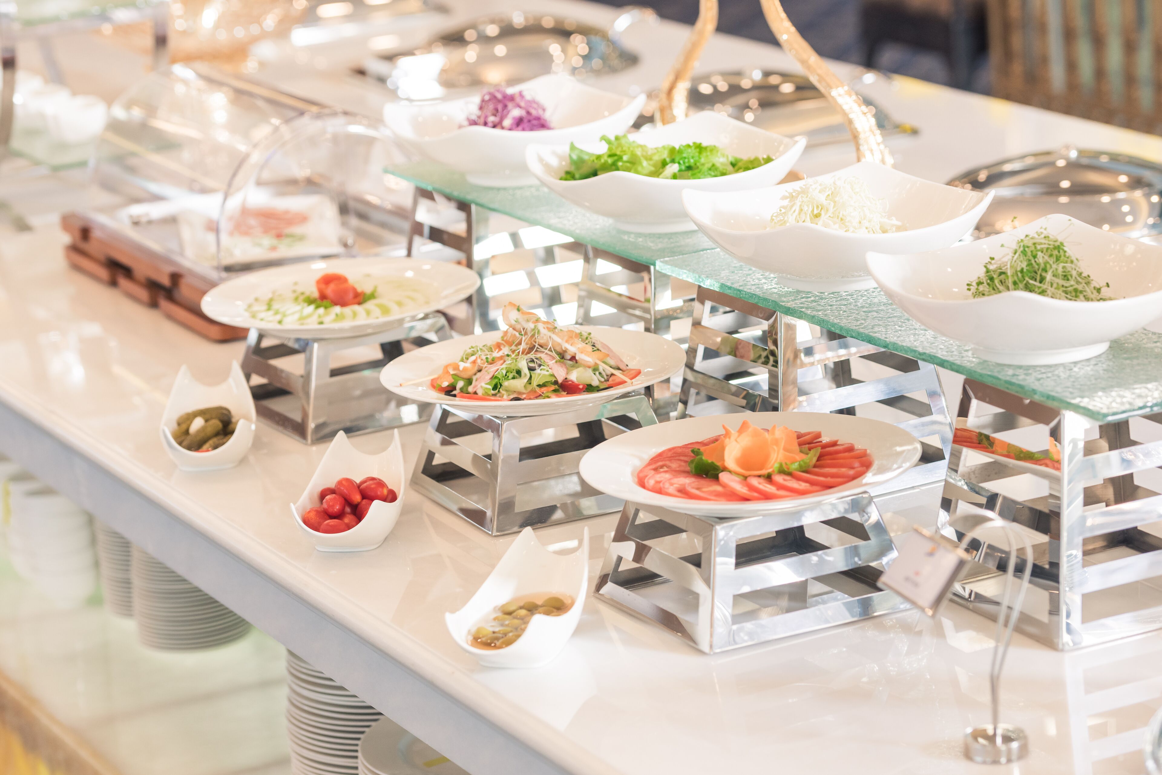 Un buffet proposant divers plats présentés dans des récipients en verre transparent, eux-mêmes posés sur des supports métalliques.