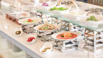 Un buffet proposant divers plats présentés dans des récipients en verre transparent, eux-mêmes posés sur des supports métalliques.