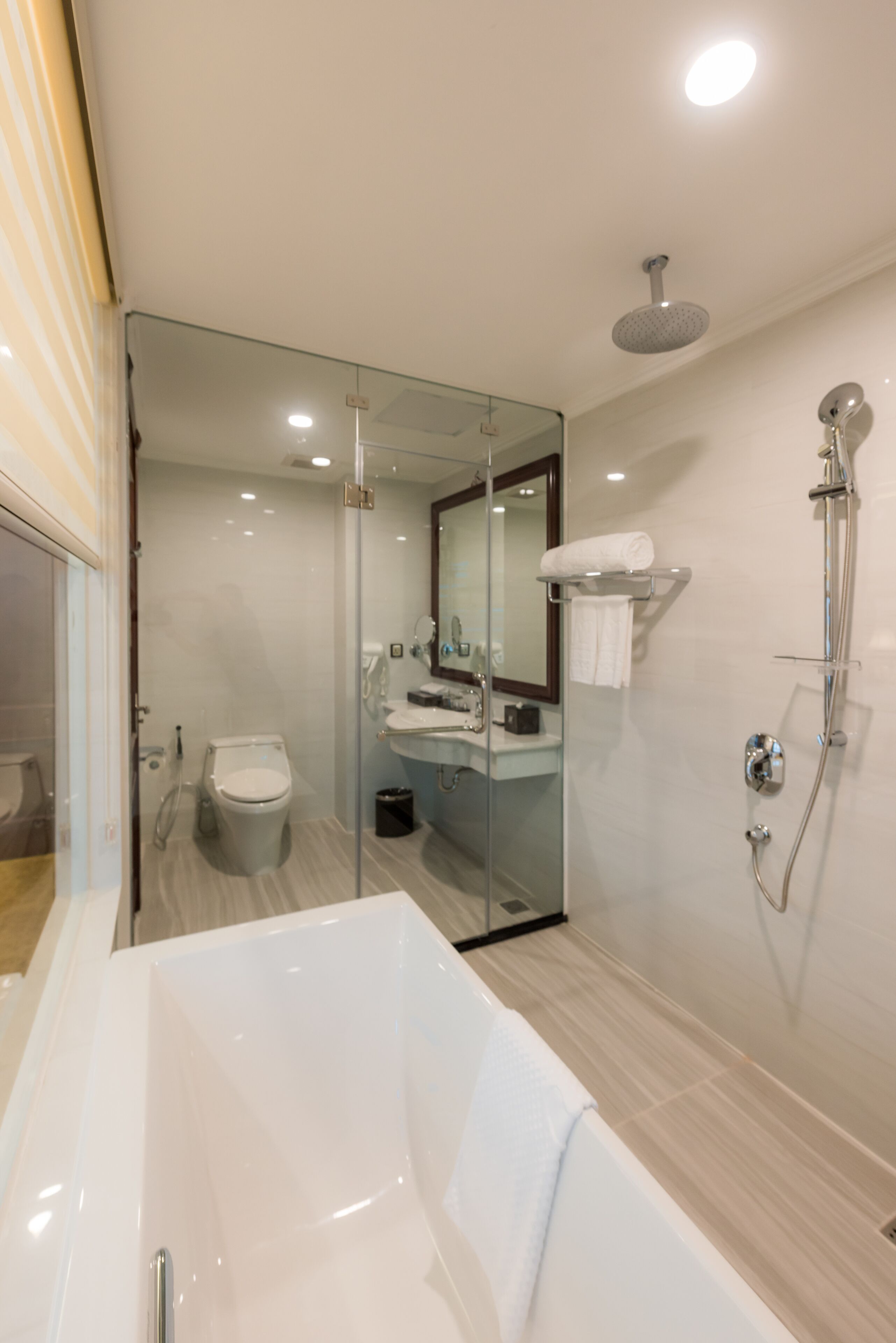 A modern bathroom with a glass-enclosed shower, a white bathtub, and a vanity with a mirror.