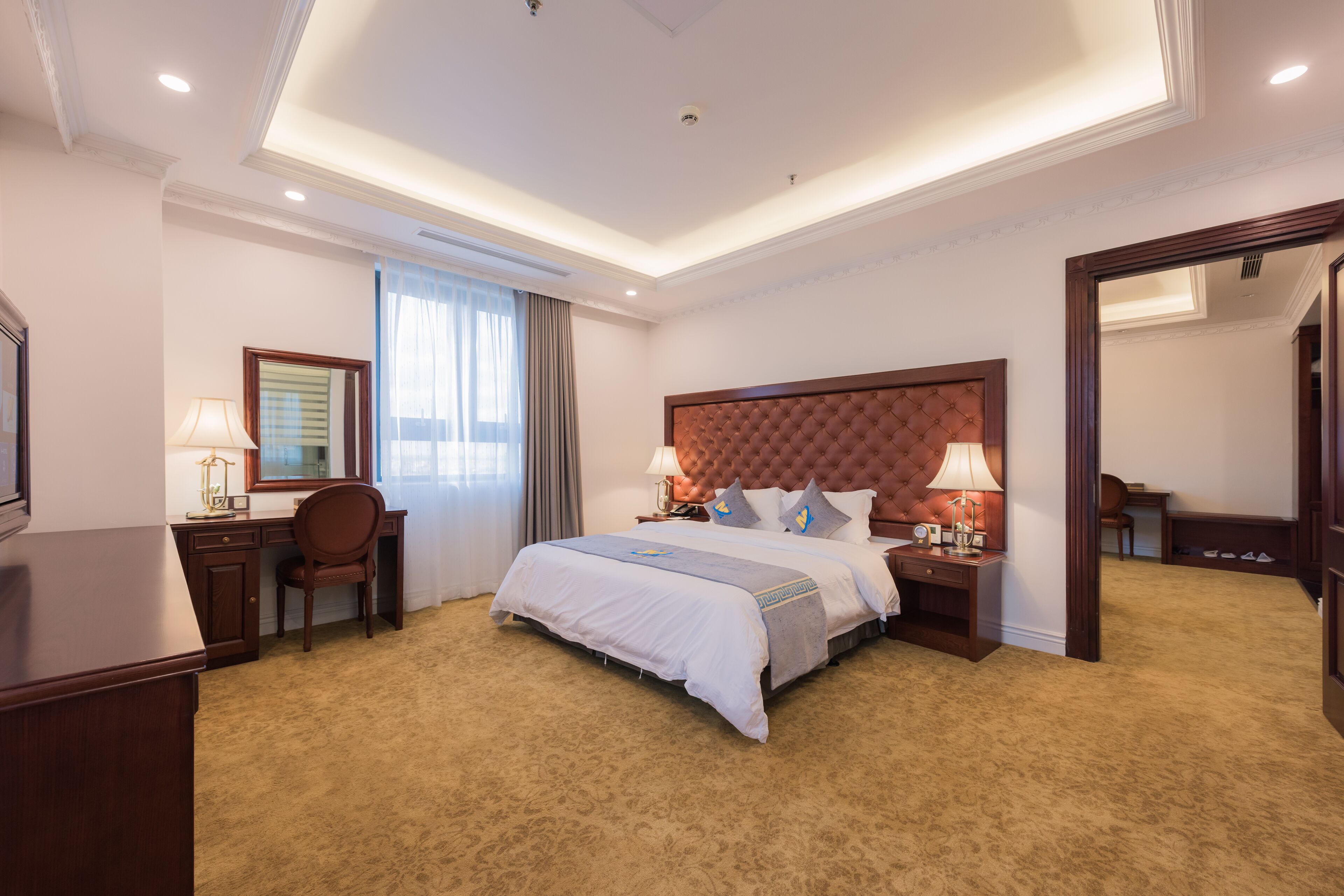 Une chambre d’hôtel avec un grand lit, un bureau, une chaise et un miroir.
