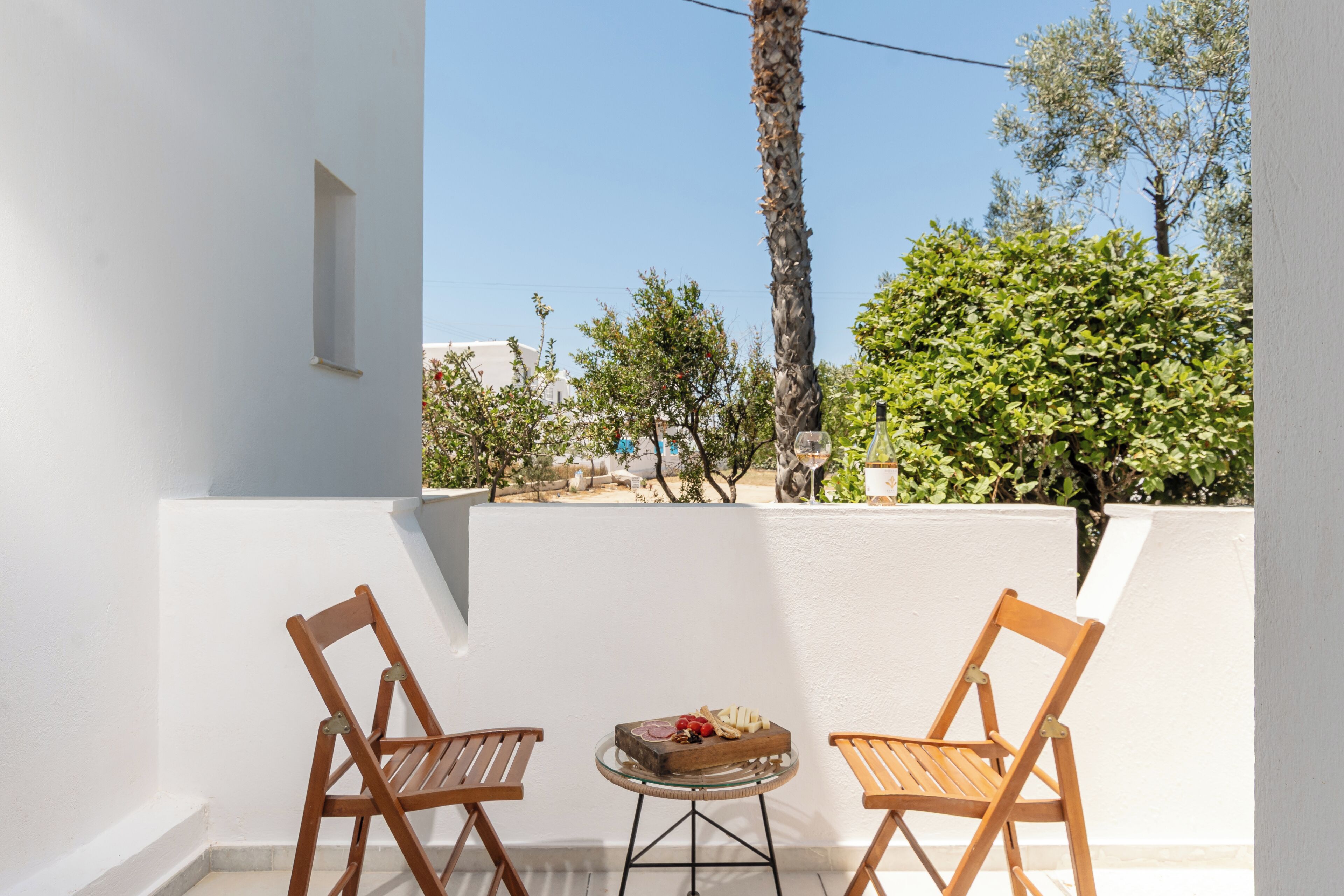 A balcony with two wooden chairs and a small table with a fruit platter.