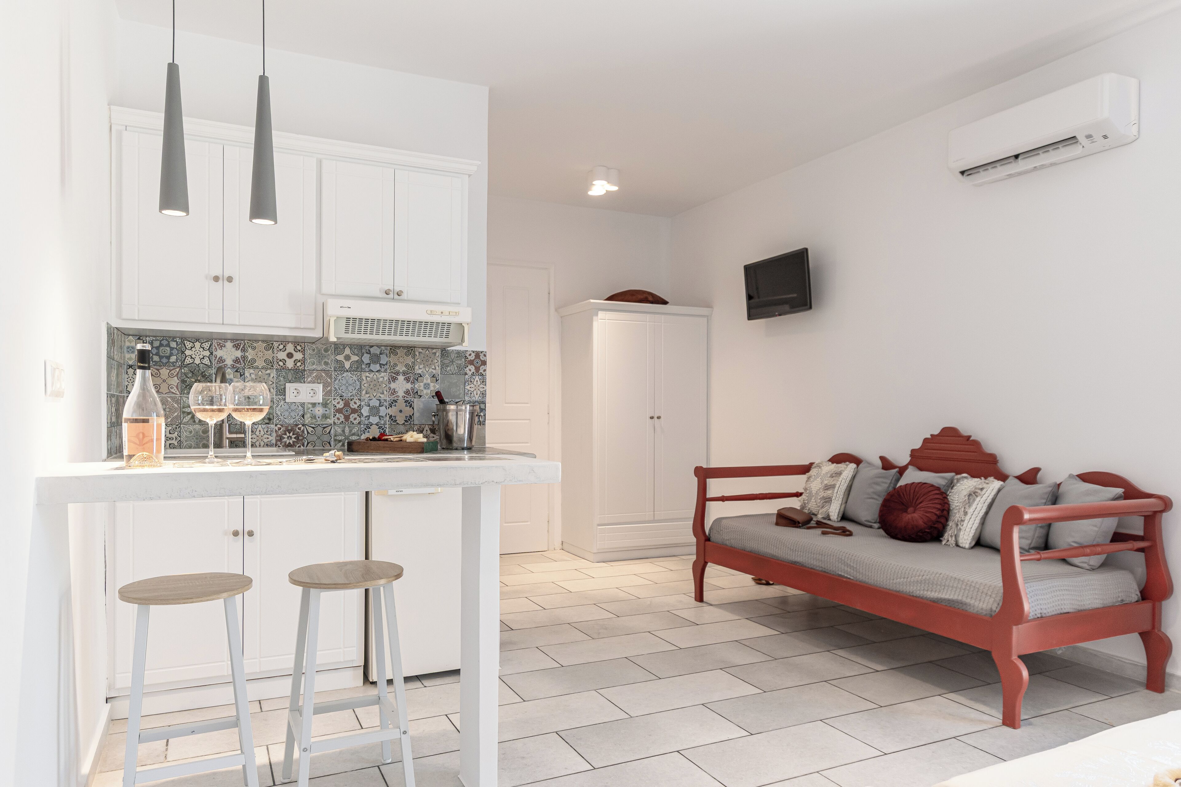 Una cocina compacta con armarios blancos, salpicadero de azulejos y una zona de bar con taburetes.