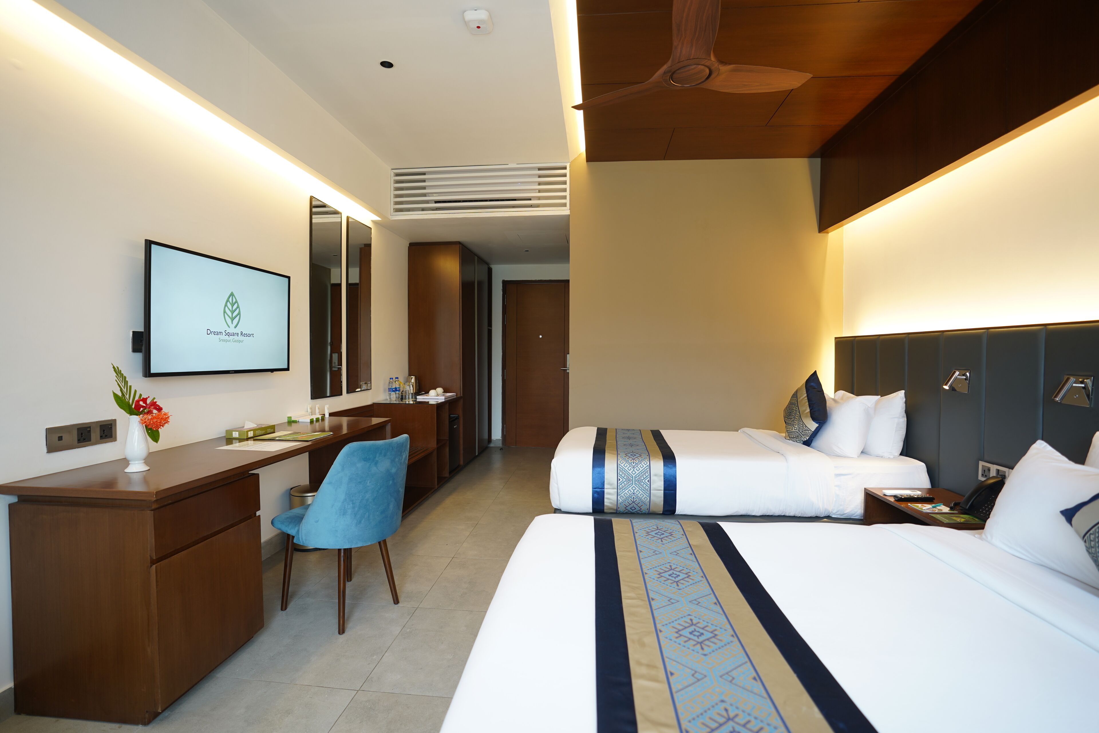 Une chambre d’hôtel avec un bureau, deux lits, une télévision et une salle de bain.