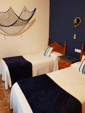 Una habitación de hotel con dos camas, cabecero de madera, mesita de noche y un calentador fijado a la pared.
