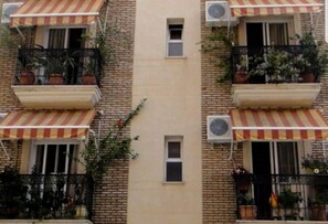 Un edificio de varios pisos con balcones, unidades de aire acondicionado y toldos a rayas.