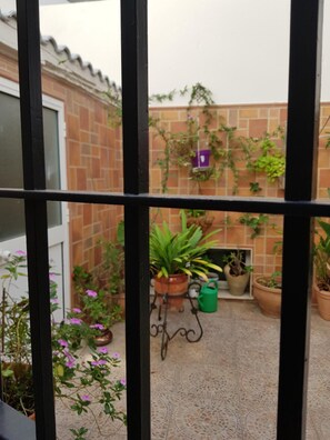 Un patio con plantas en macetas, una mesa pequeña y un muro de ladrillo.