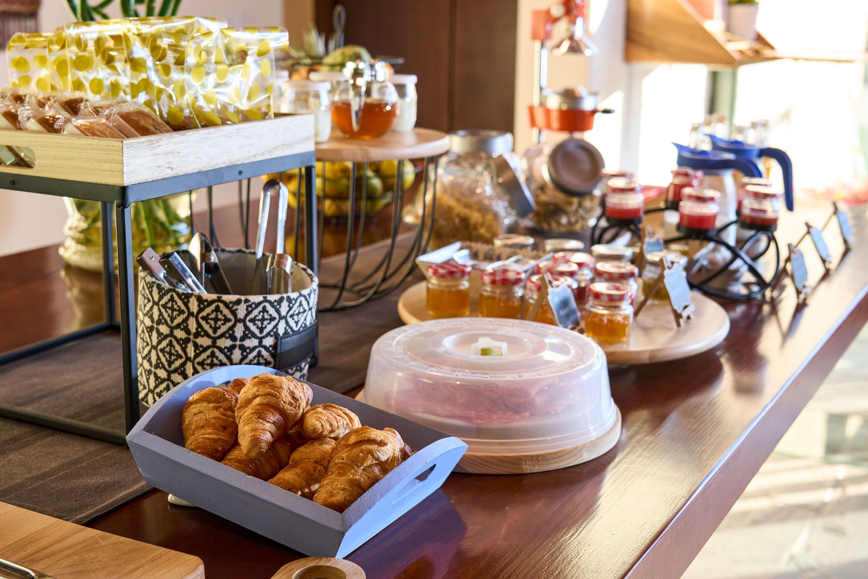 Un bufé de desayuno con pasteles, mermeladas y tarros de miel.