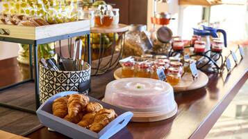 Un bufé de desayuno con pasteles, mermeladas y tarros de miel.