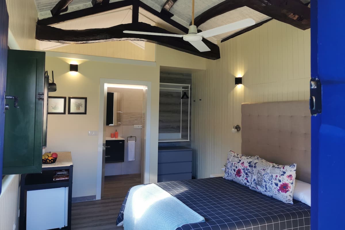 A bedroom with a bed, a dresser, a mirror, and a ceiling fan.