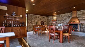 A rustic interior with a stone wall, wooden ceiling, and a fireplace.