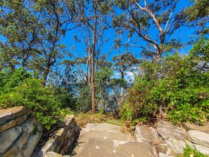 Stroll through the serene park, surrounded by lush trees and vibrant vegetation along a winding stone pathway.