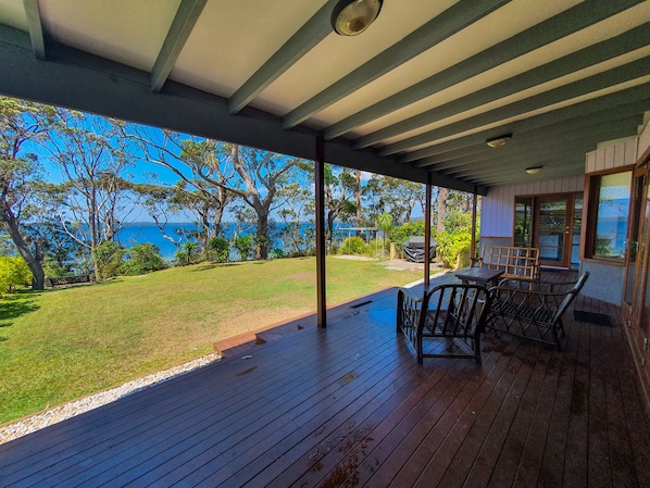 Relax on the covered deck overlooking the ocean and lush green surroundings.