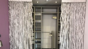 Un dressing avec une porte, doté d’une armoire à miroir, d’étagères et d’un espace pour suspendre les vêtements.
