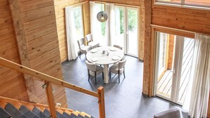 A wooden interior with a round dining table, chairs, and a hanging light fixture. - Lovely home in HEEL with lake view (HEEL)