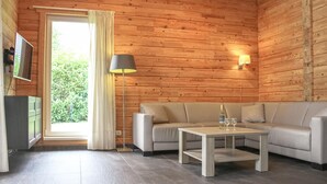 A cozy room with a wooden interior, a sofa, a coffee table, a lamp, and a TV. - Lovely home in HEEL with lake view (HEEL)