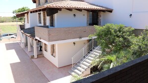 A two-story house with a stone facade, a tiled roof, and a balcony. - B Holidays Casa Vacanze (Cabras)