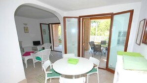 A dining area with a round table and chairs, a small kitchen area, and a sliding glass door leading to an outdoor patio.