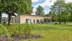 A modern building with a flat roof, large windows, and a well-maintained lawn.