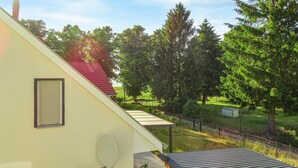 A residential building with a sloped roof, satellite dish, and a fenced yard with trees.