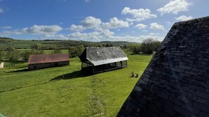 Paisaje rural con un granero y una casa de techo inclinado.