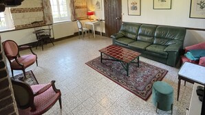 Un salón acogedor con un sofá verde, un tapete estampado y techo de madera.