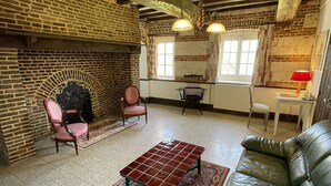 Una sala de estar acogedora con chimenea, sofá de cuero y alfombra estampada.