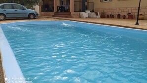 A swimming pool with a covered patio area, a parked car, and potted plants. - Cortijo oliveras Moratalla (Moratalla)