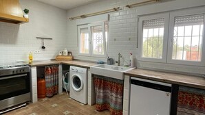 A compact kitchen with a stove, oven, washing machine, and sink. - Cortijo oliveras Moratalla (Moratalla)