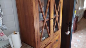 A wooden cabinet with glass doors, a roll of toilet paper, and a small dog keychain on the door handle. - Cortijo oliveras Moratalla (Moratalla)