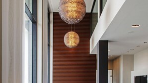 A modern lobby with a central seating area, a large decorative light fixture, and a view of the hallway. - Steigenberger Airport Hotel Berlin (Schoenefeld)