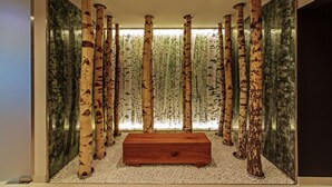A room with birch tree columns, a wooden bench, and a wall with a forest mural. - Steigenberger Airport Hotel Berlin (Schoenefeld)