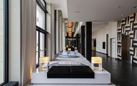 A modern hotel lobby with a central seating area, large windows, and a patterned wall design.