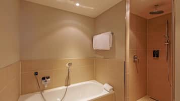 Ein modernes Badezimmer mit Badewanne, einer gläsernen Duschkabine und beige gefliesten Wänden.